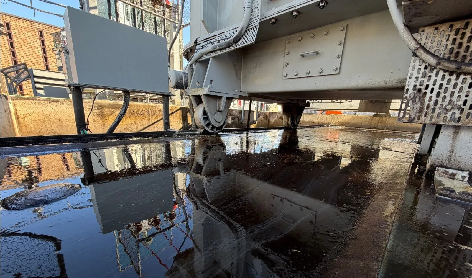 Oily water pooled across a transformer bund floor beneath the equipment, before remediation.