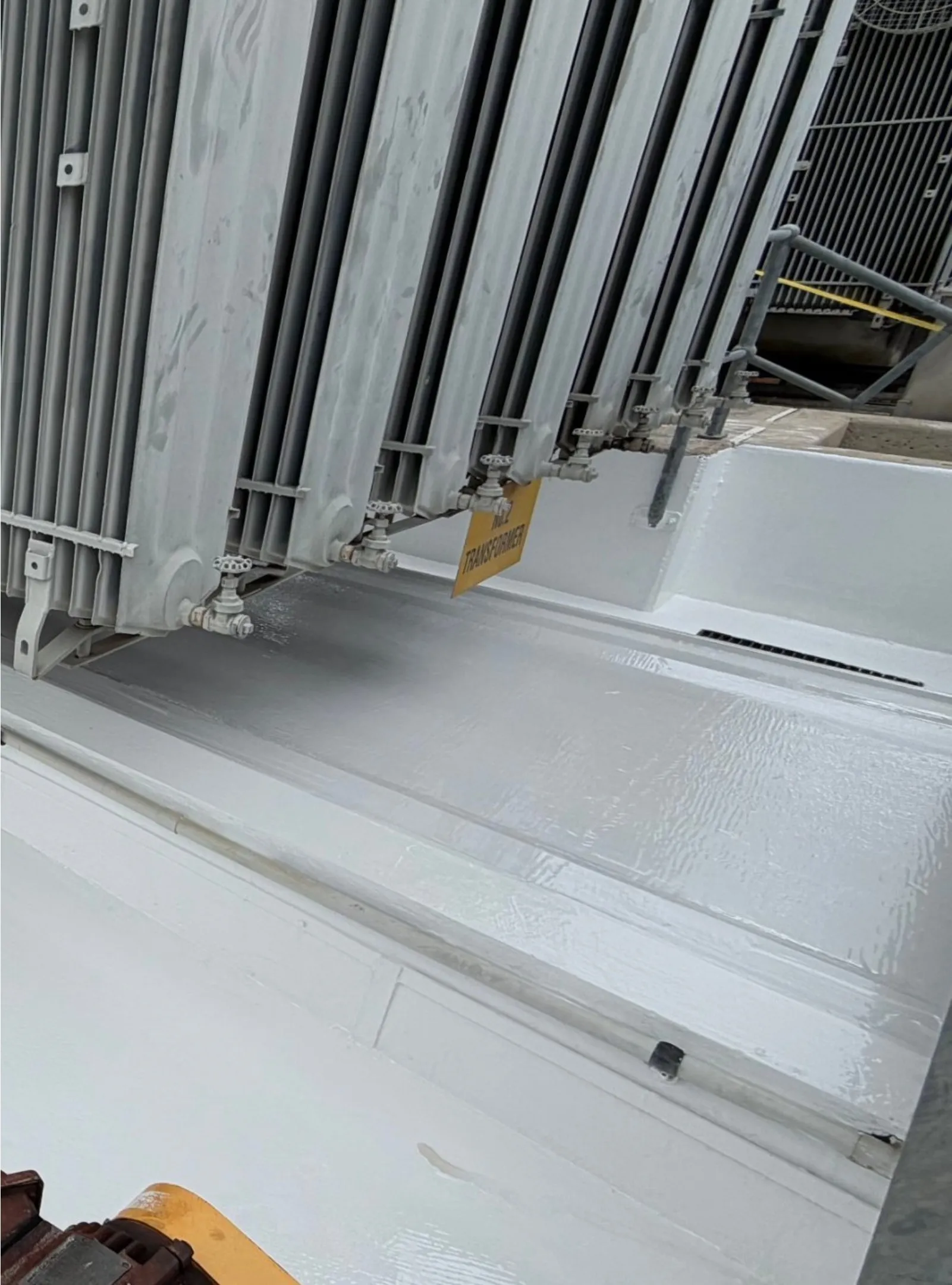 Completed white lining along the base of a transformer radiator bank.