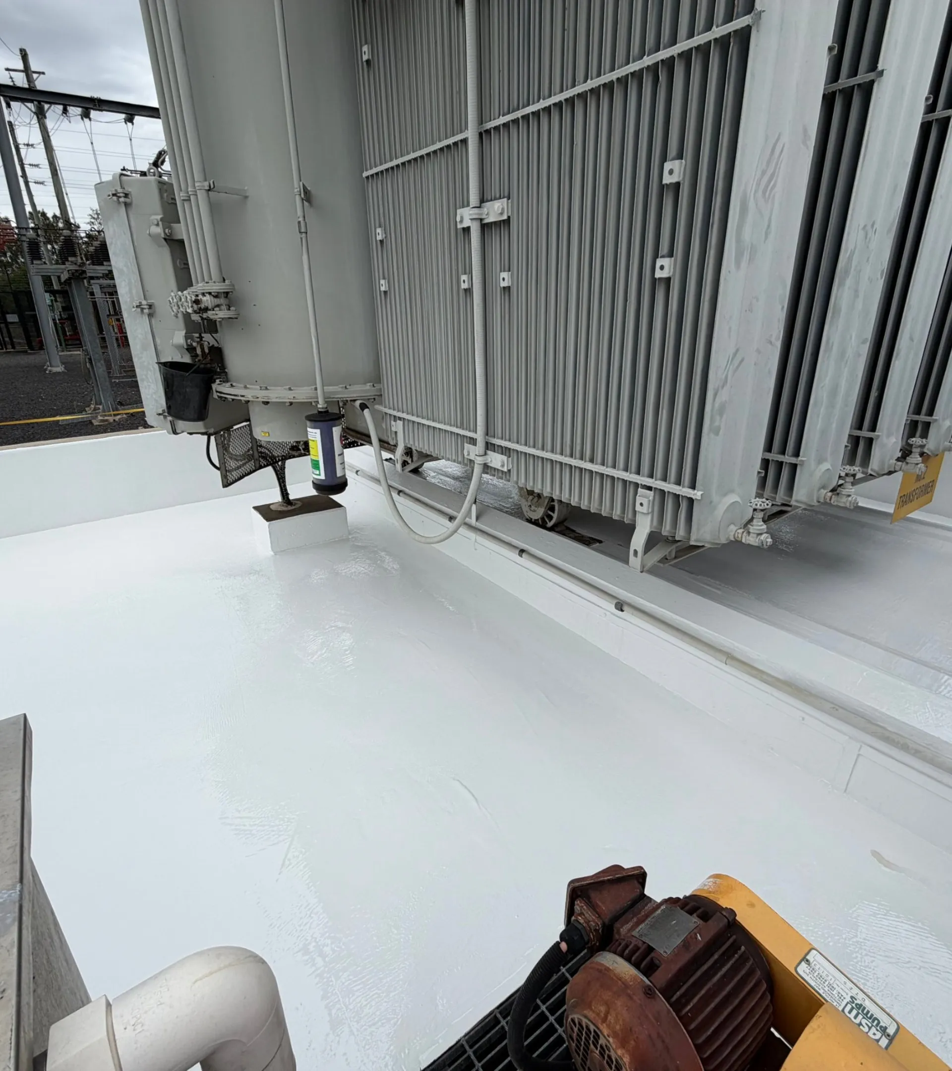 A transformer bund with a newly applied white protective lining on the floor and walls.