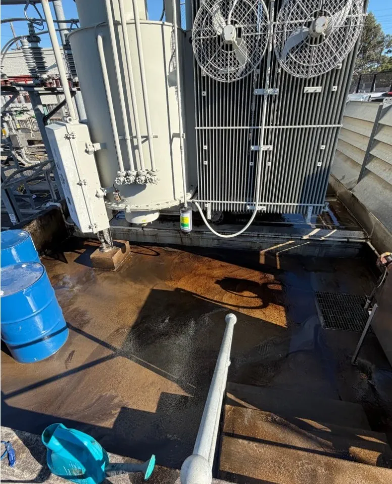 Transformer bund floor covered in oil residue before decontamination.
